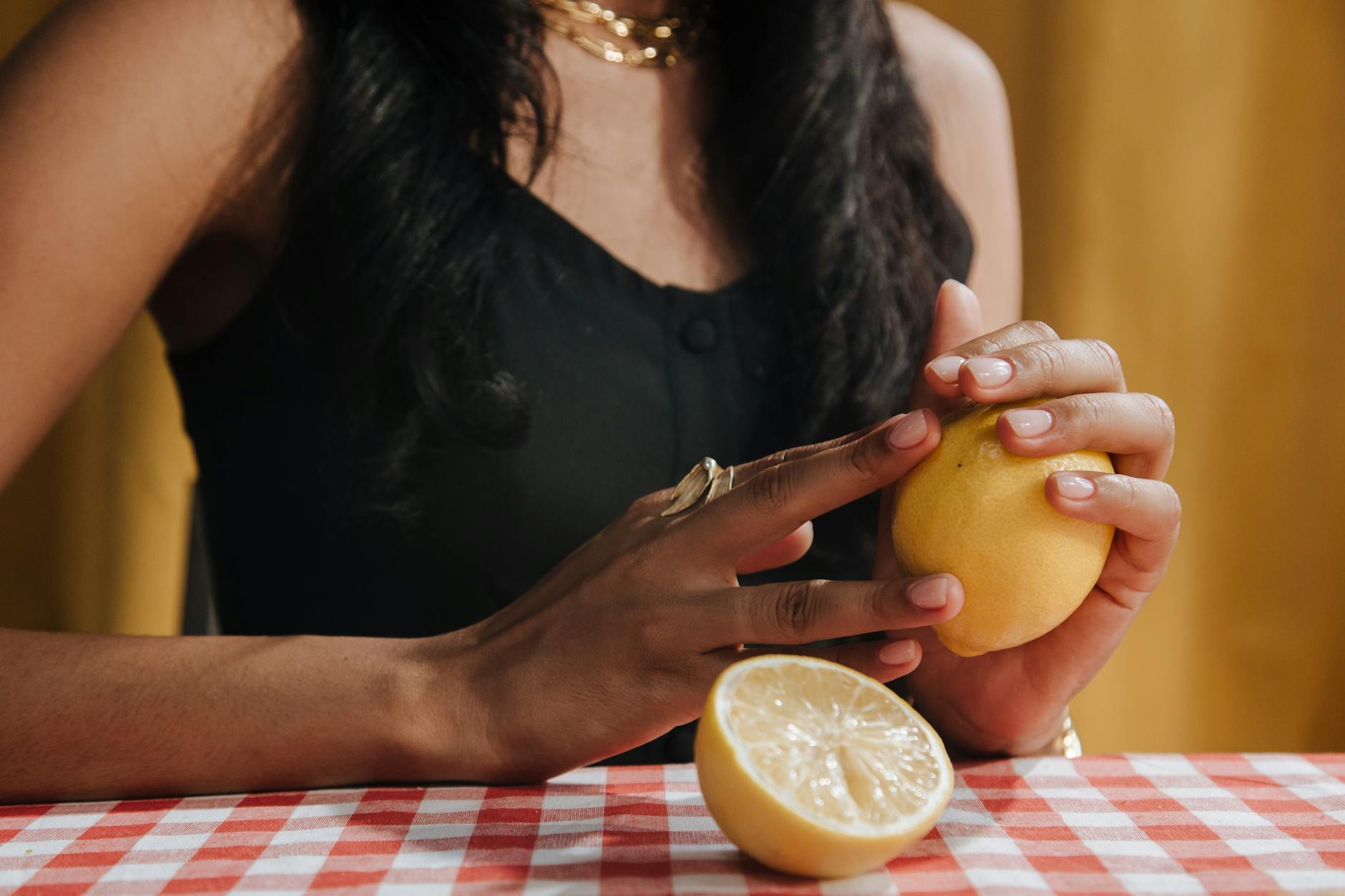Hand holding a modern orange vibrator against a minimalistic purple backdrop