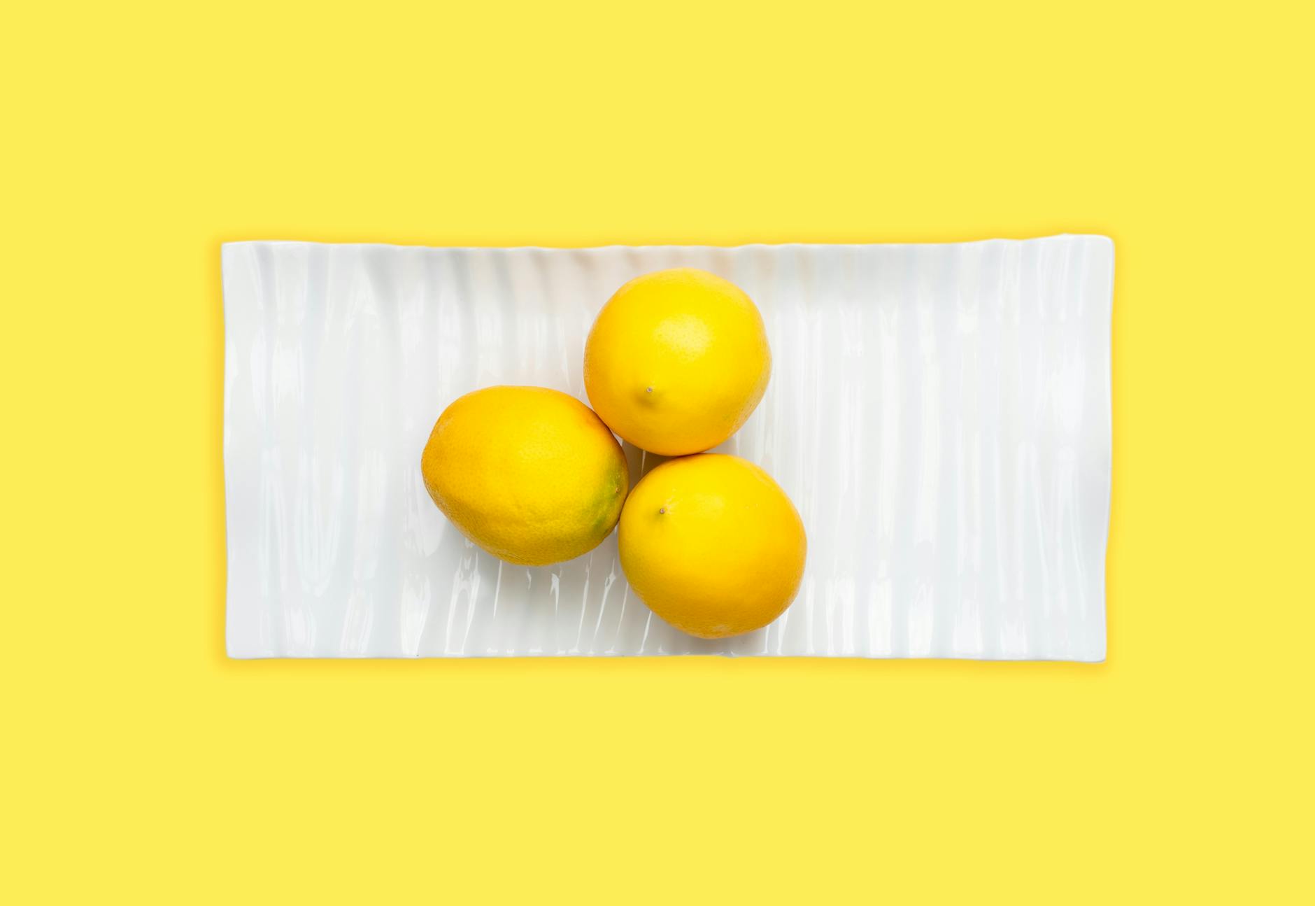 Fresh lemons on a white plate with yellow background, symbolizing restoration and renewal after stress