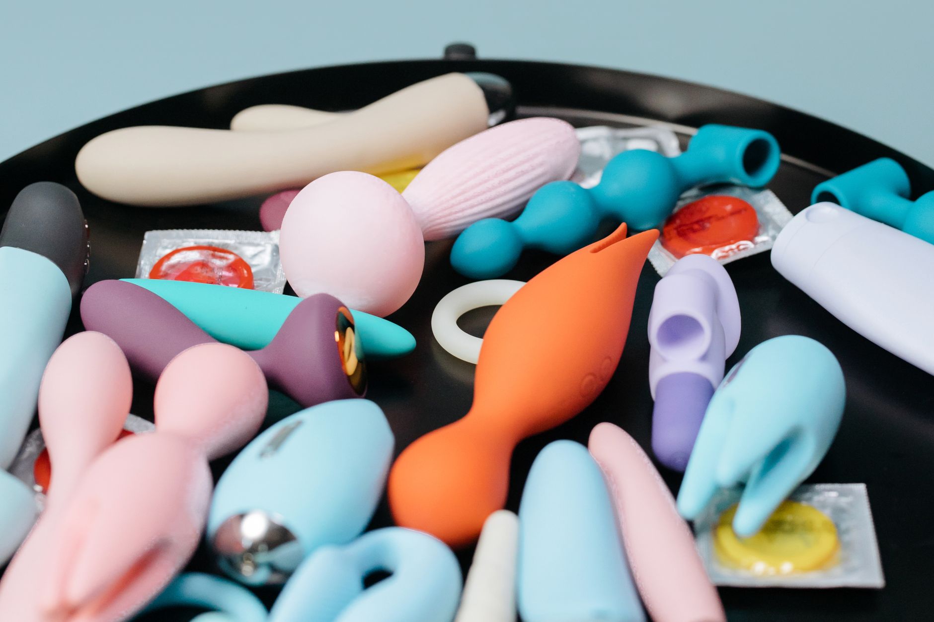 Close-up of a woman holding a pink vibrator with art books in the background