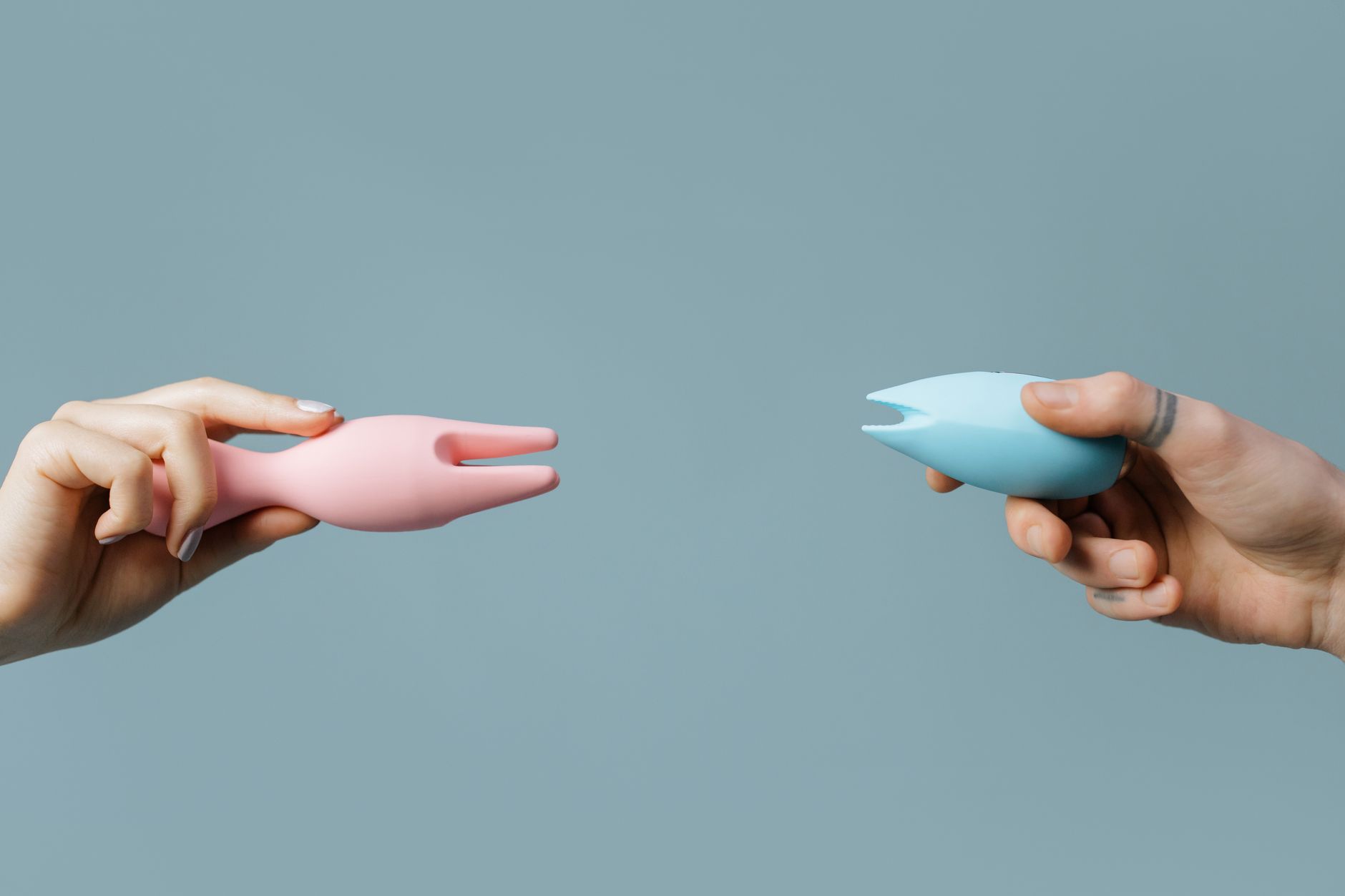 Two vibrators held side by side on a pastel surface
