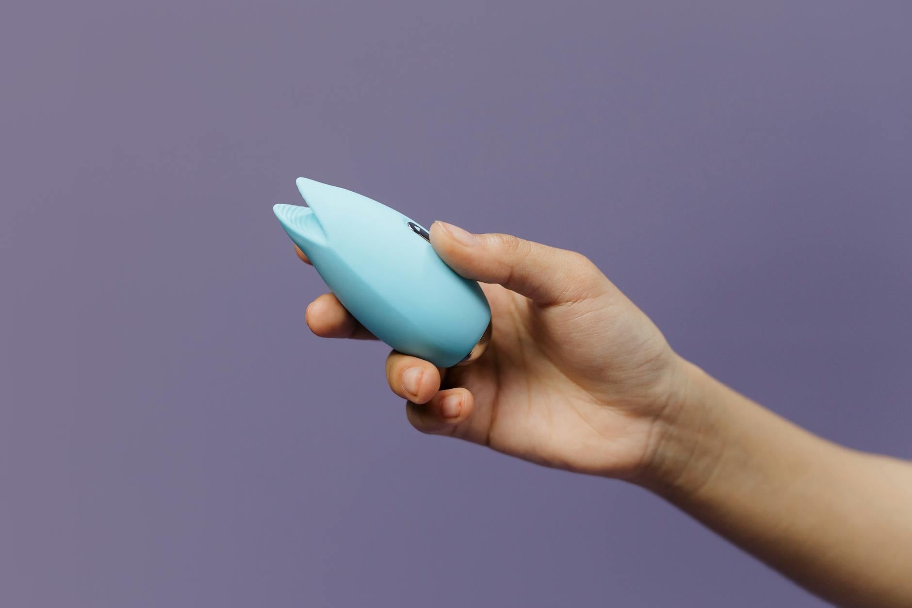 A blue silicone vibrator held in hand, symbolizing intimacy and shared pleasure between partners